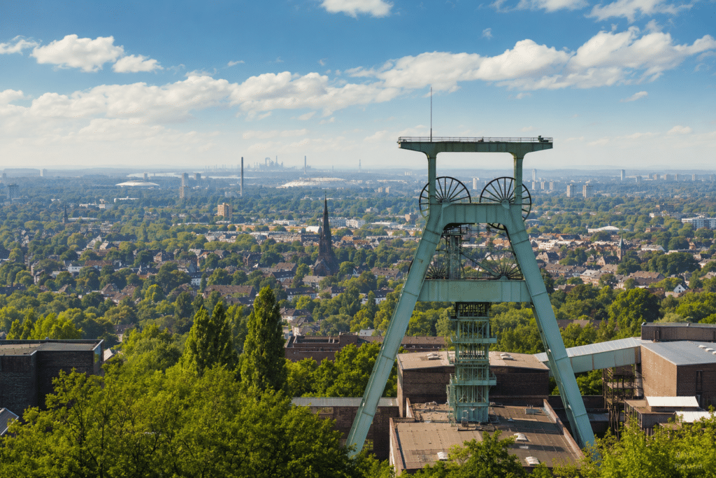 Förderturm vor einer grünen Stadtlandschaft im Ruhrgebiet mit weiter Aussicht über die Region